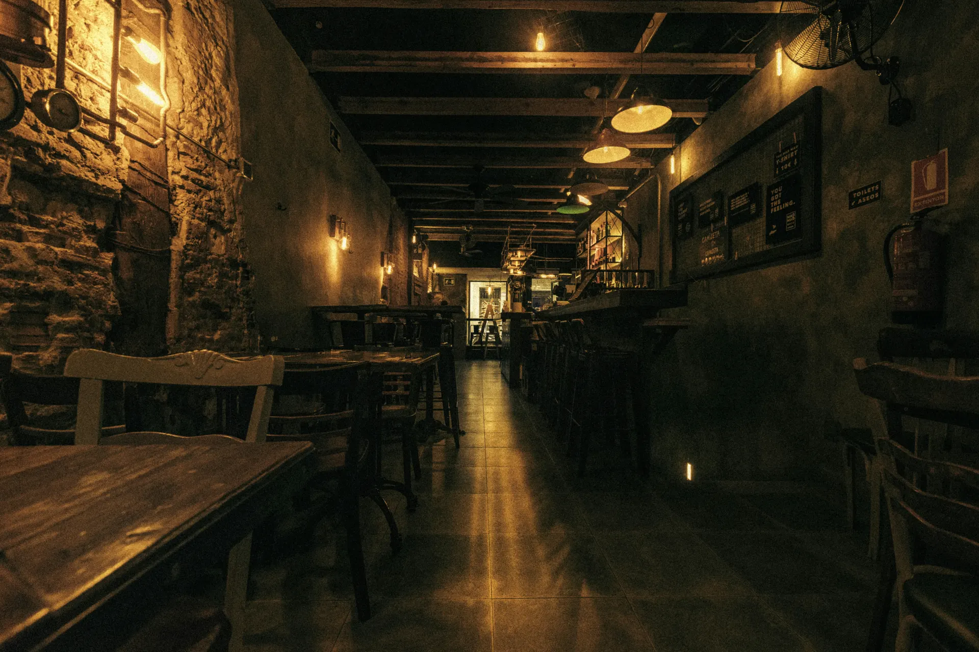 Narrow restaurant dining room with wooden tables and warm pendant lights