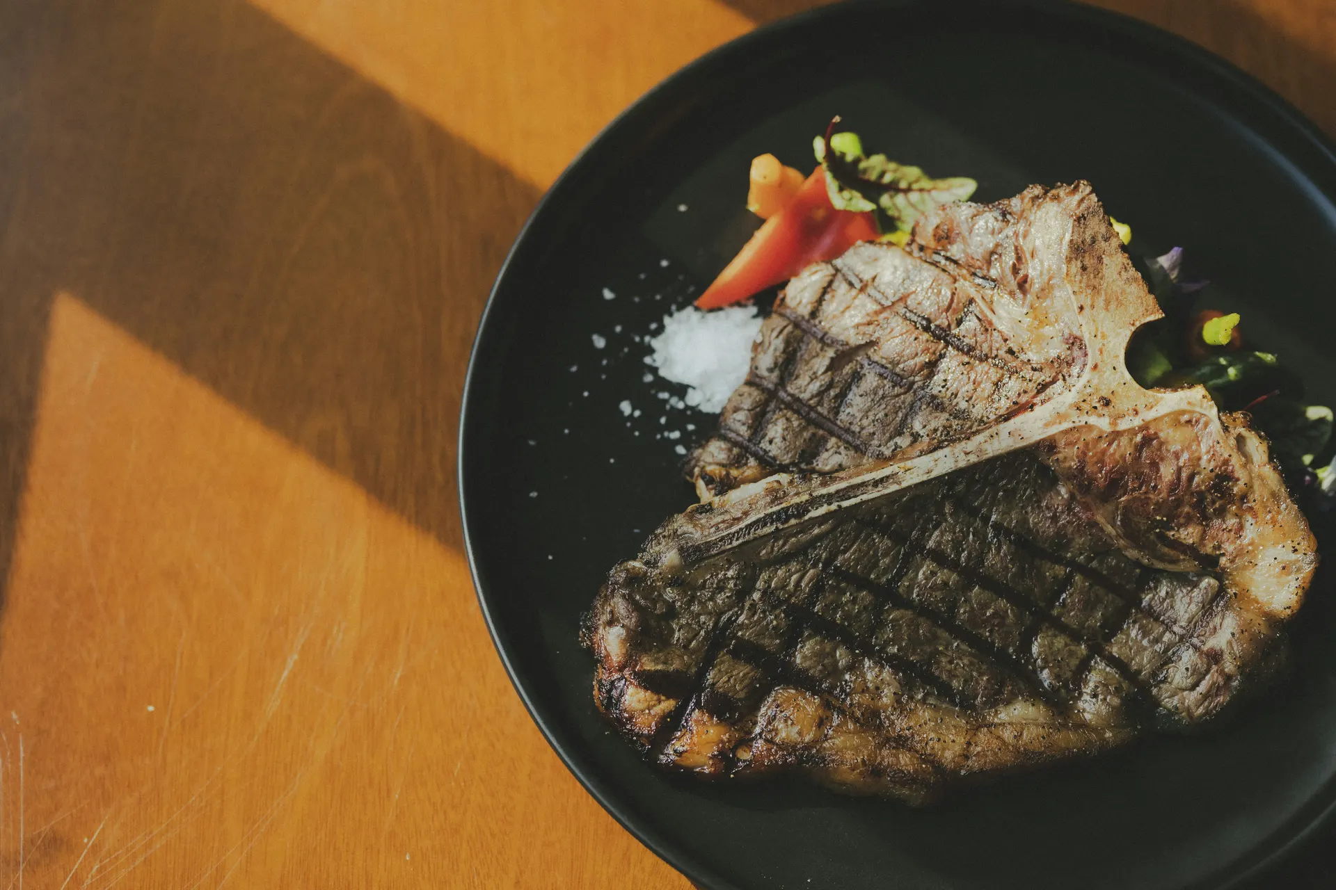 Grilled steak served on a black plate with a small garnish
